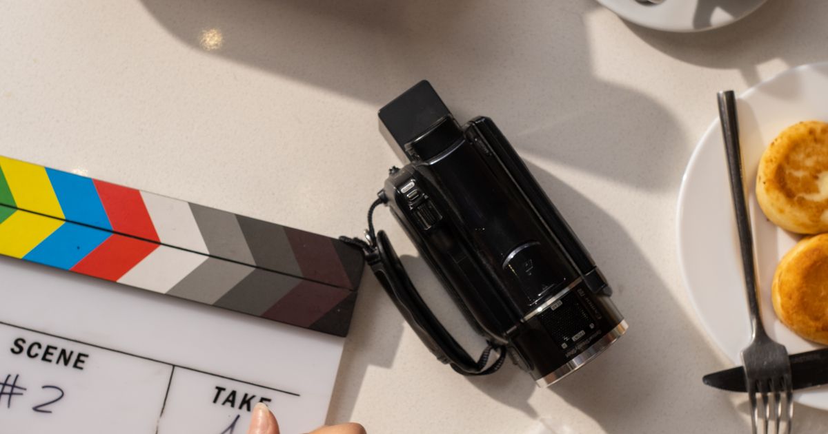 Claquete e câmera de vídeo sobre uma mesa, prontas para uma gravação