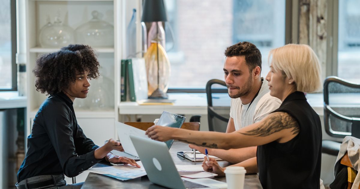 Profissionais avaliando perfis em reunião de trabalho com laptop