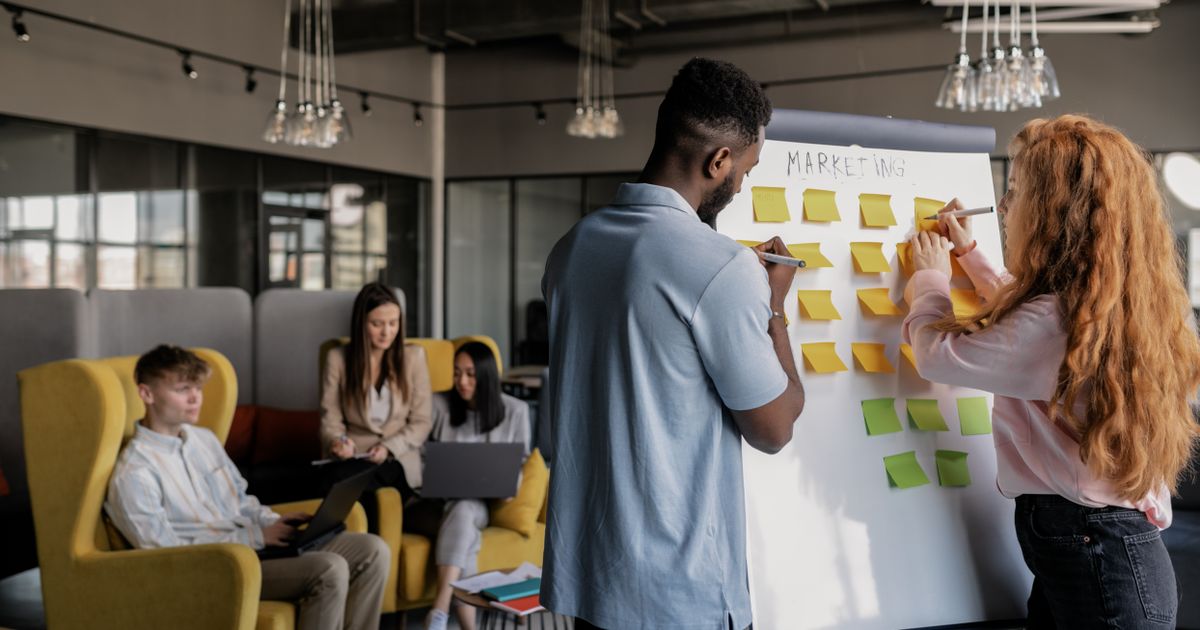 Equipe de marketing planejando campanha com post-its em flipchart