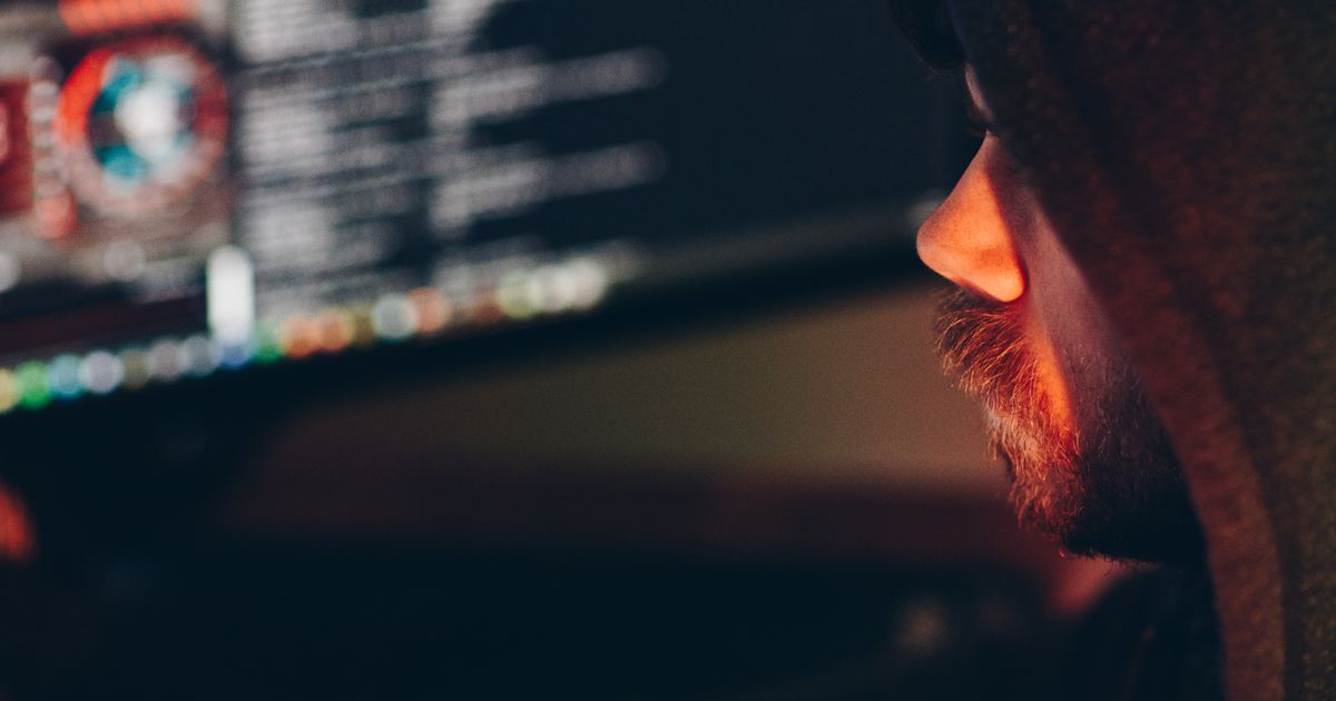 Analista examinando dados na tela do computador em ambiente escuro