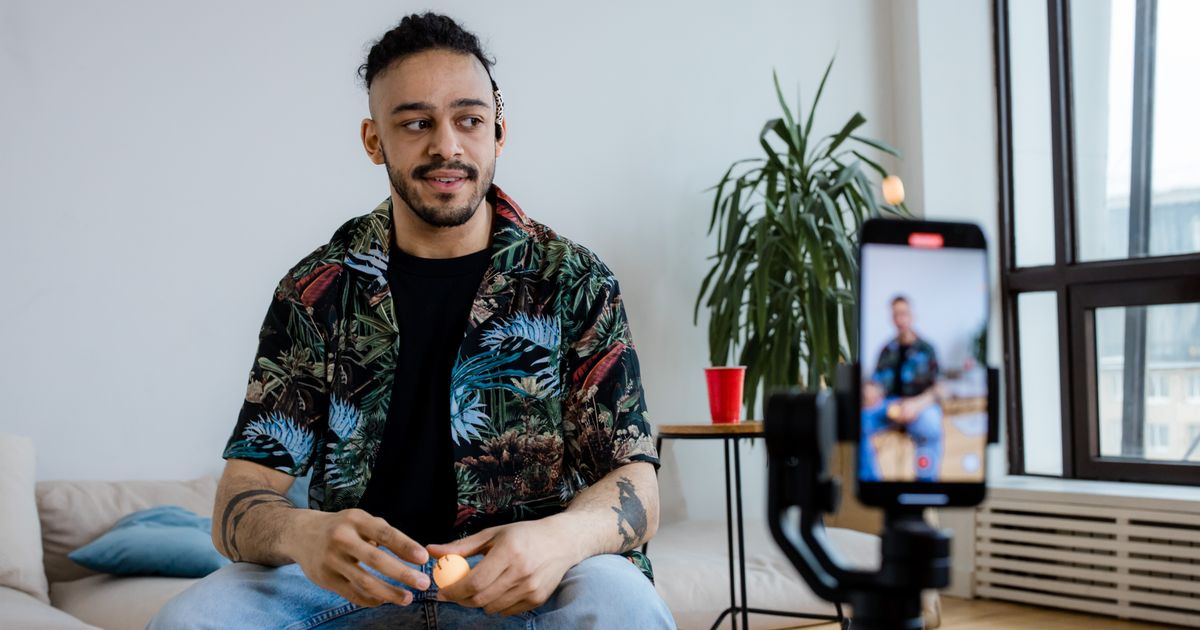 Criador de conteúdo gravando um vídeo com o celular em um tripé na sala de casa