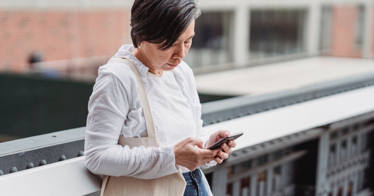 Mulher consultando o celular em uma passarela da cidade