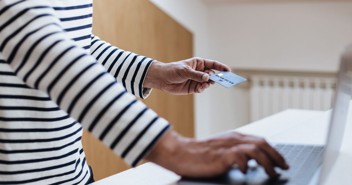 Pessoa comprando online com cartão de crédito na mão