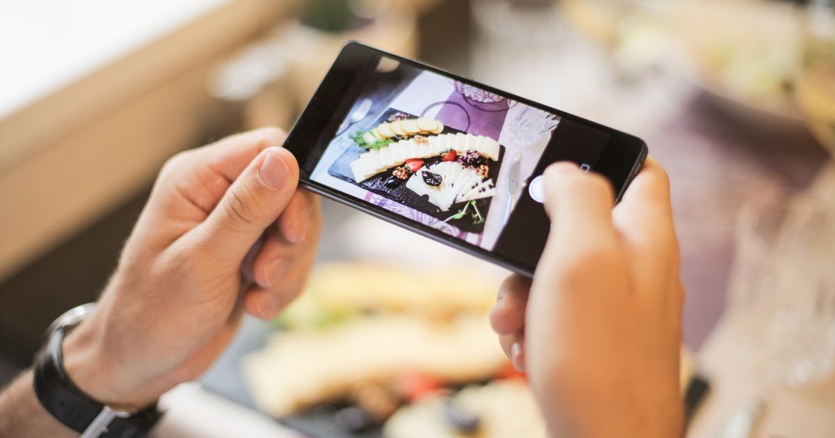 Pessoa fotografando um prato de comida com o celular