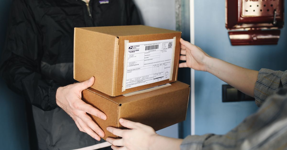 Mãos entregando e recebendo caixas de encomenda com etiqueta de envio