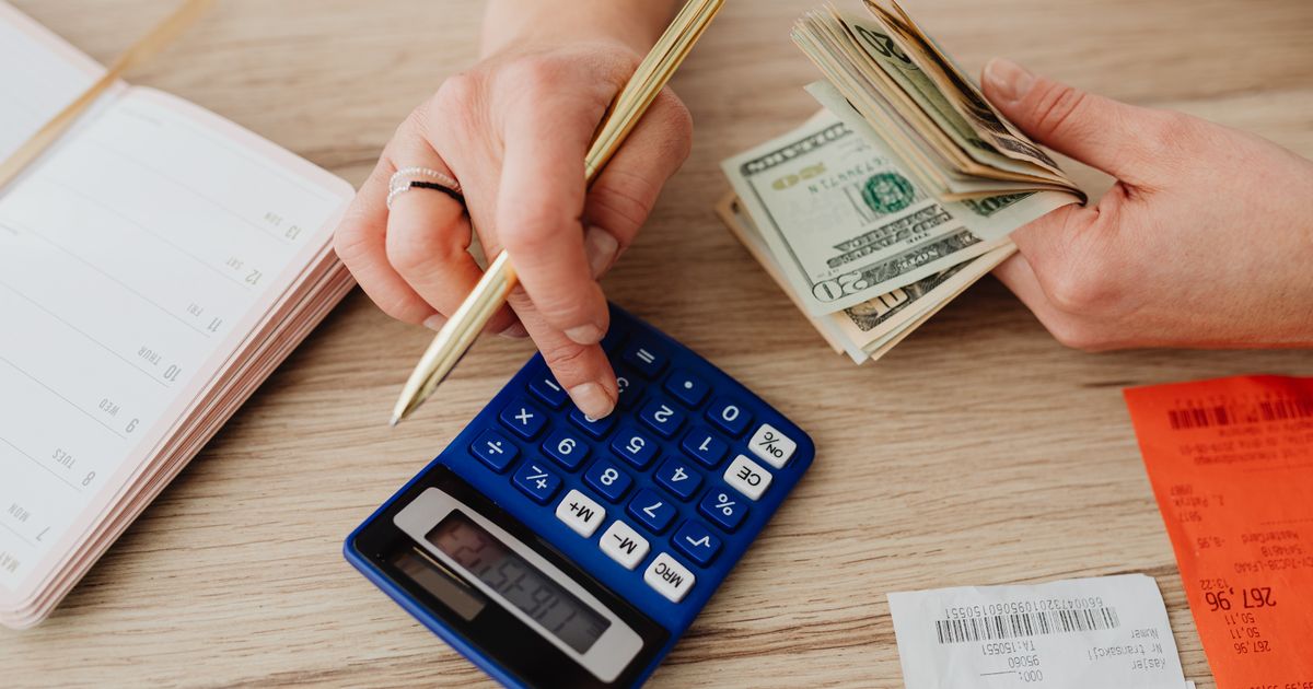 Mãos calculando orçamento com calculadora, dinheiro e agenda