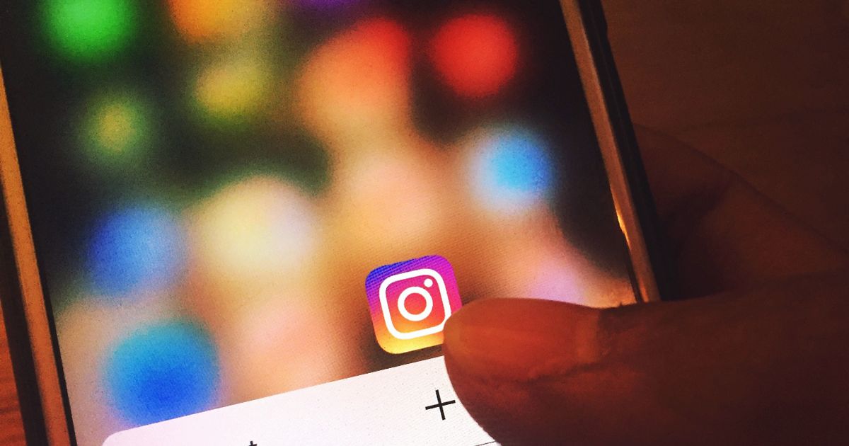 Dedo tocando o ícone do Instagram na tela de um smartphone